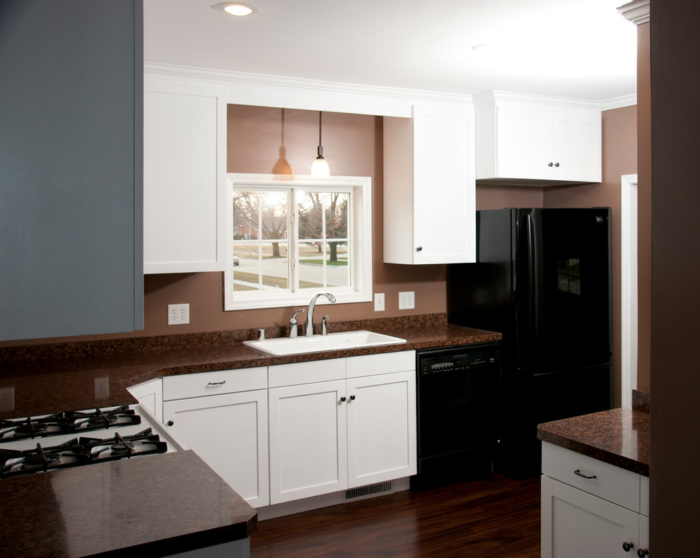 Exempel på ett mellanstort, avskilt modernt l-kök, med en dubbel diskho, skåp i shakerstil, vita skåp, laminatbänkskiva, brunt stänkskydd, svarta vitvaror och mörkt trägolv
