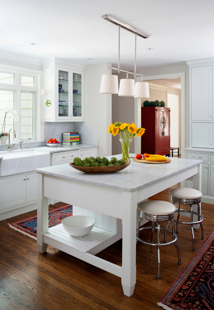 Inredning av ett klassiskt avskilt, mellanstort linjärt kök, med en rustik diskho, skåp i shakerstil, vita skåp, mörkt trägolv, en köksö, marmorbänkskiva, grått stänkskydd, stänkskydd i marmor, rostfria vitvaror och brunt golv