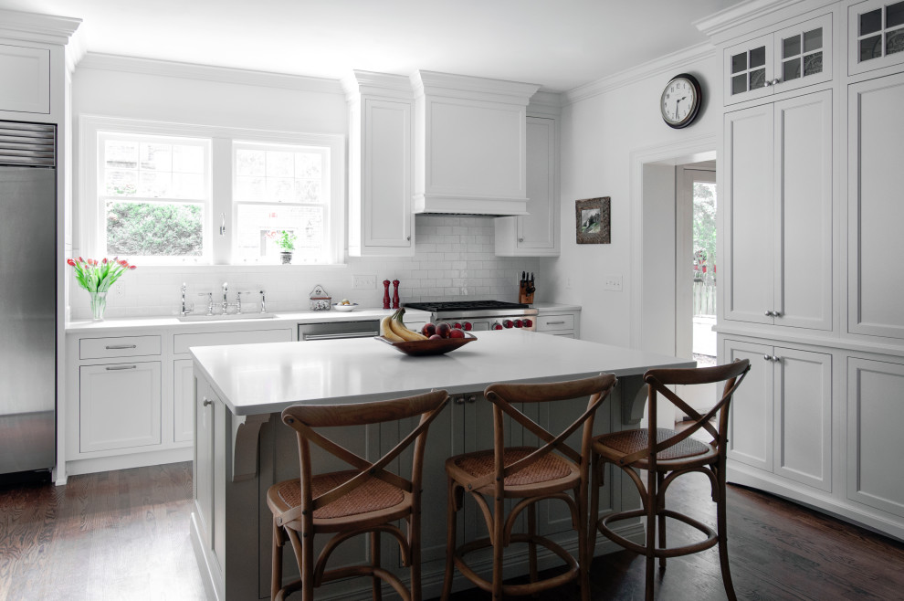 Design ideas for a medium sized traditional galley kitchen/diner in Nashville with a submerged sink, beaded cabinets, white cabinets, engineered stone countertops, white splashback, ceramic splashback, stainless steel appliances, dark hardwood flooring, an island, brown floors and white worktops.