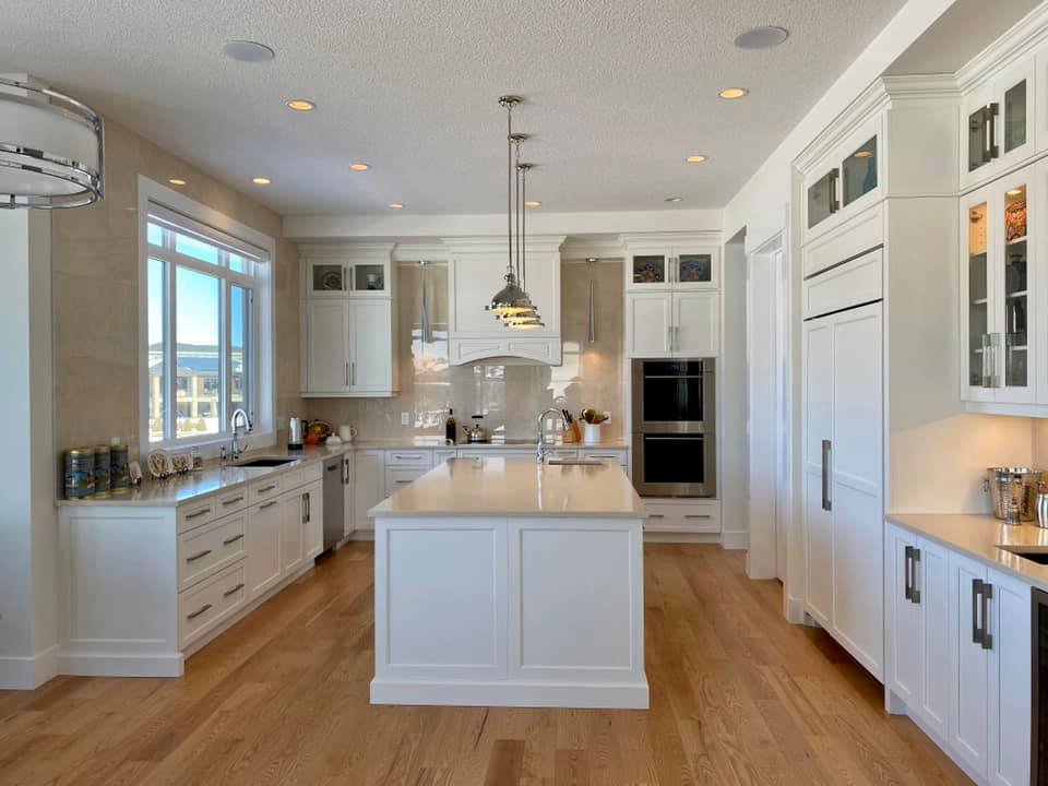 Photo of a traditional u-shaped kitchen in Edmonton with a submerged sink, shaker cabinets, white cabinets, engineered stone countertops, beige splashback, brick splashback, stainless steel appliances, plywood flooring, an island, purple floors and beige worktops.