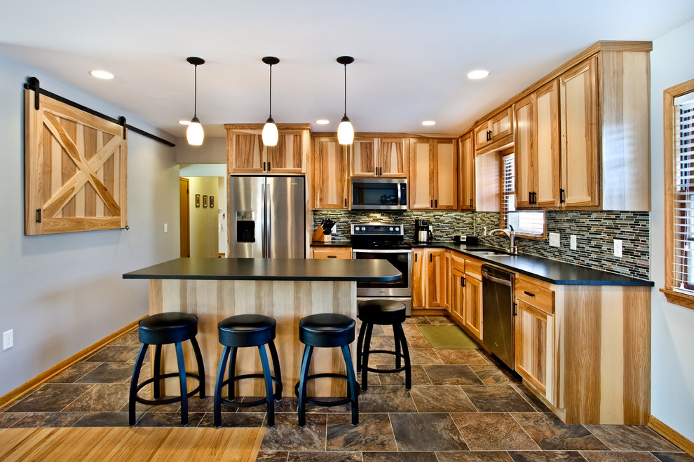 Example of a mid-sized classic l-shaped vinyl floor eat-in kitchen design in Minneapolis with an undermount sink, recessed-panel cabinets, light wood cabinets, multicolored backsplash, stainless steel appliances, granite countertops, glass tile backsplash and an island