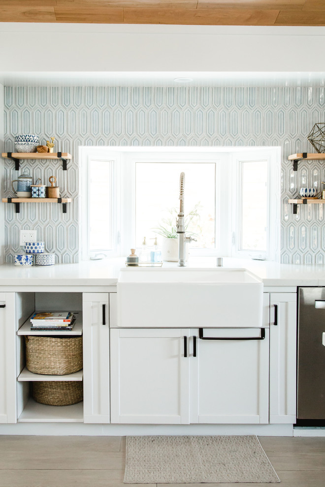 Bild på ett stort maritimt vit vitt kök, med en rustik diskho, skåp i shakerstil, svarta skåp, bänkskiva i kvarts, blått stänkskydd, stänkskydd i keramik, rostfria vitvaror, klinkergolv i porslin, en halv köksö och brunt golv