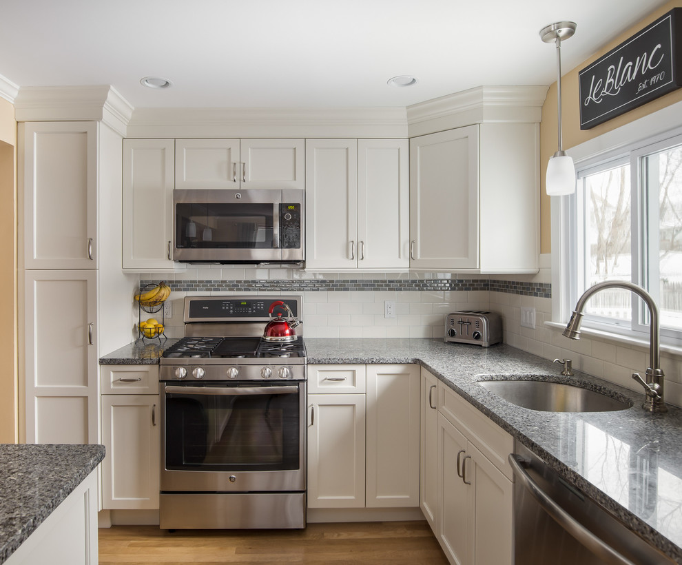 Inspiration for a small transitional l-shaped light wood floor eat-in kitchen remodel in Boston with an undermount sink, shaker cabinets, yellow cabinets, granite countertops, multicolored backsplash, subway tile backsplash, stainless steel appliances and an island