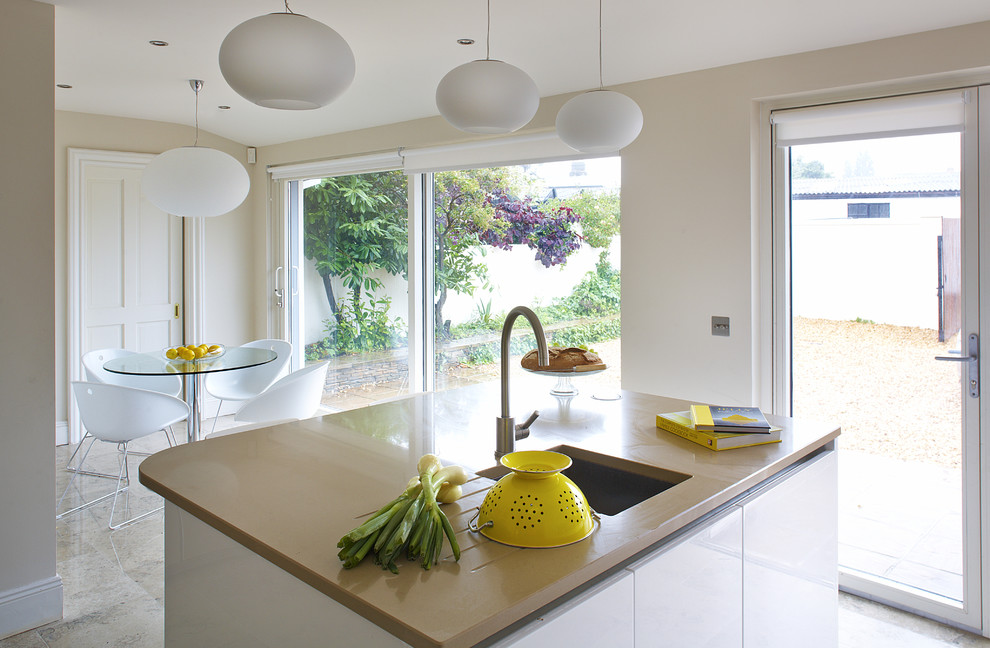 Modern inredning av ett kök och matrum, med en undermonterad diskho, släta luckor och vita skåp