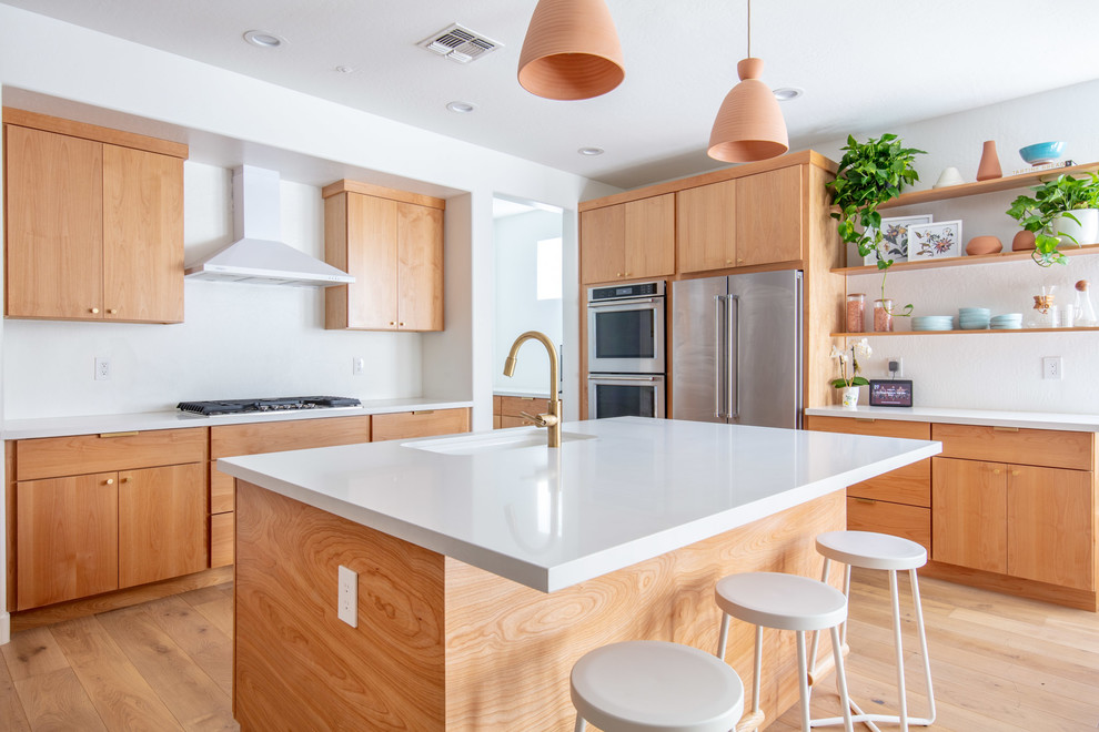 Inspiration for a mid-sized mid-century modern u-shaped light wood floor and brown floor eat-in kitchen remodel in Phoenix with an undermount sink, flat-panel cabinets, light wood cabinets, quartz countertops, white backsplash, stainless steel appliances, an island and white countertops