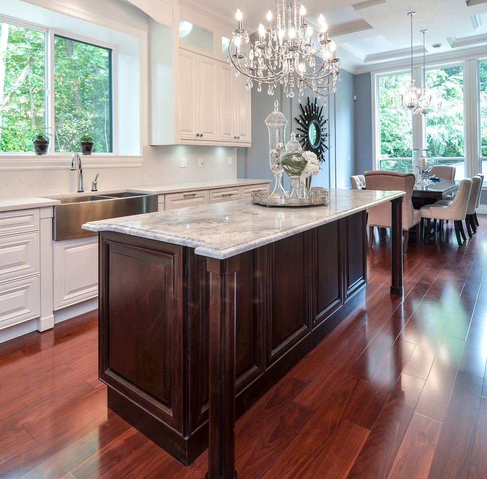 Inspiration for a large modern l-shaped medium tone wood floor eat-in kitchen remodel in Vancouver with raised-panel cabinets, white cabinets, an island, granite countertops, a farmhouse sink, stainless steel appliances, white backsplash and ceramic backsplash