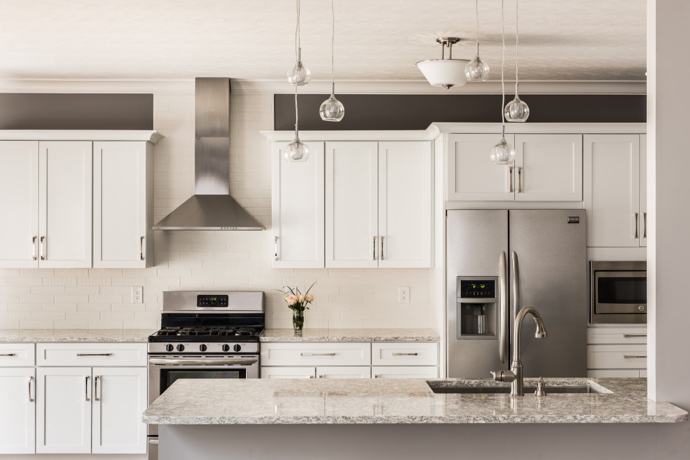 Bild på ett mellanstort vintage flerfärgad flerfärgat kök, med en undermonterad diskho, luckor med infälld panel, vita skåp, bänkskiva i kvarts, vitt stänkskydd, stänkskydd i stenkakel, rostfria vitvaror, vinylgolv, en halv köksö och beiget golv