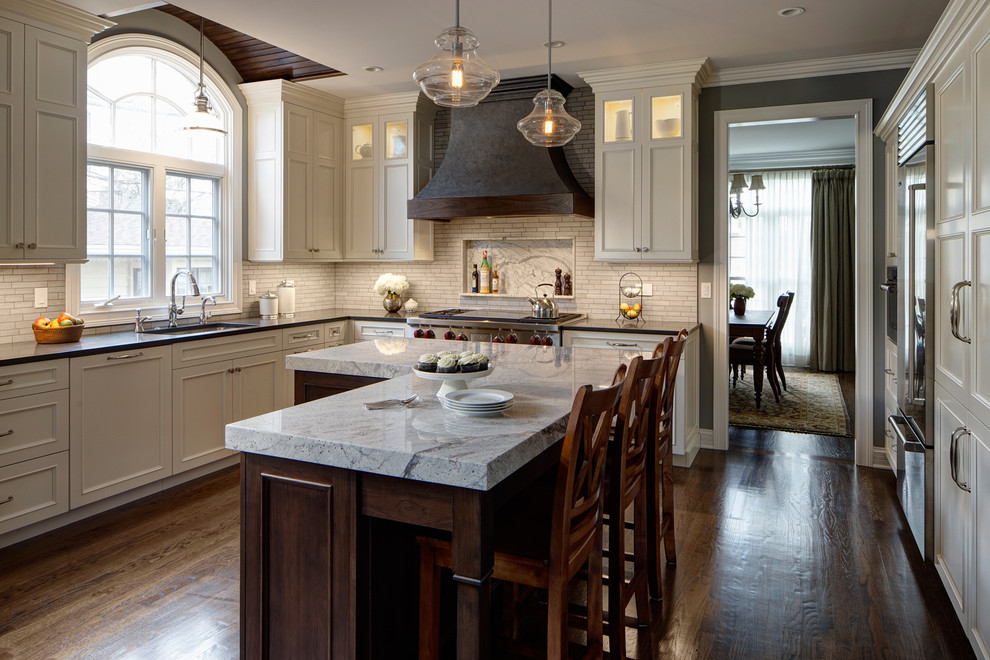 Inspiration for a mid-sized transitional l-shaped medium tone wood floor eat-in kitchen remodel in Chicago with an undermount sink, white cabinets, gray backsplash, stainless steel appliances, an island and granite countertops