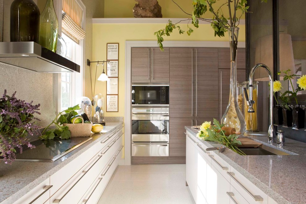Photo of a contemporary galley kitchen in DC Metro with a submerged sink, flat-panel cabinets, white cabinets, grey splashback, stainless steel appliances and an island.