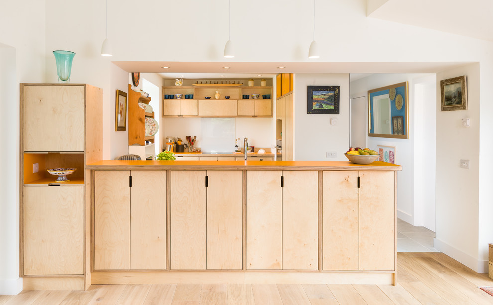 Medium sized scandi l-shaped open plan kitchen in Other with light wood cabinets, wood worktops, white splashback, glass sheet splashback, integrated appliances and a breakfast bar.