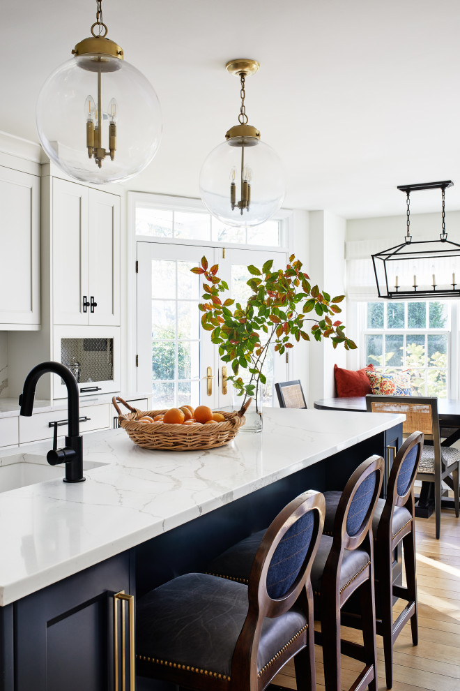 Inspiration for a large classic kitchen in DC Metro with shaker cabinets, blue cabinets, engineered stone countertops, white splashback, stone slab splashback, light hardwood flooring, an island and white worktops.