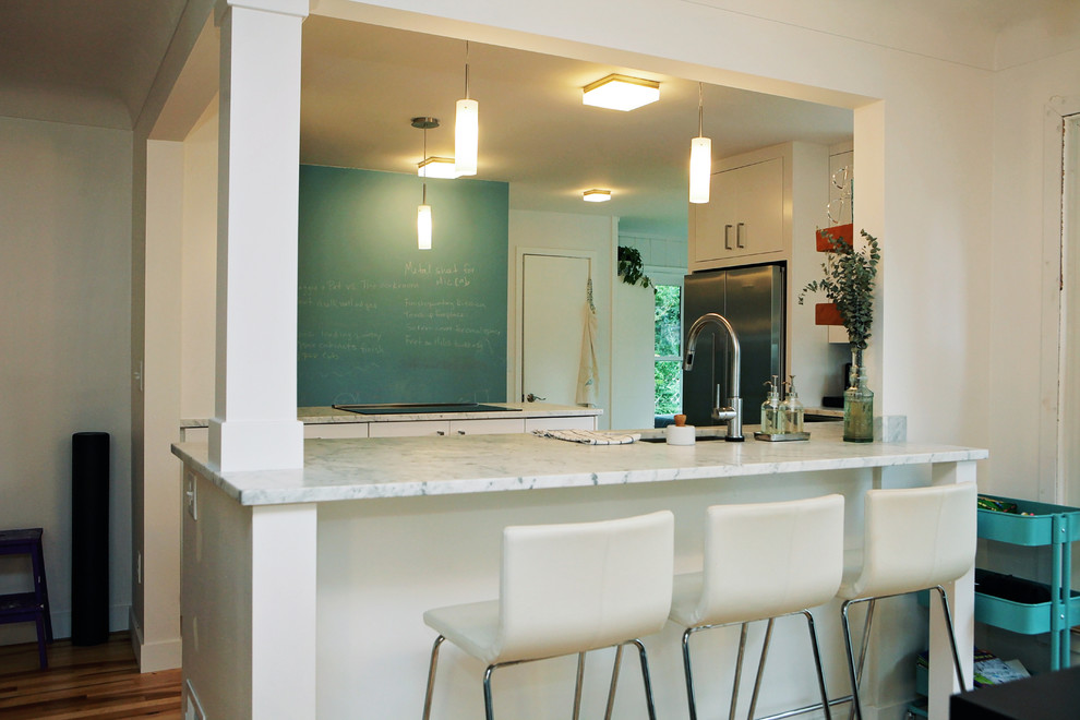 Foto di una cucina contemporanea di medie dimensioni con ante lisce, ante bianche, top in marmo, paraspruzzi bianco, elettrodomestici in acciaio inossidabile e pavimento in legno massello medio