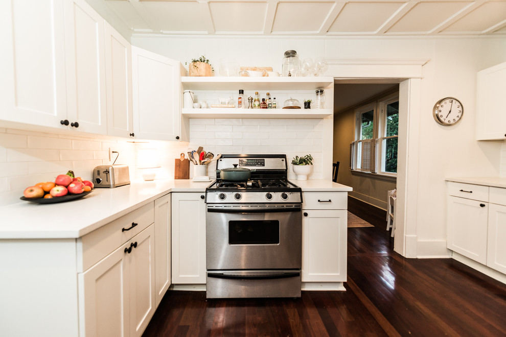 Foto på ett mellanstort retro kök, med en rustik diskho, skåp i shakerstil, vita skåp, bänkskiva i kvarts, vitt stänkskydd, stänkskydd i keramik, rostfria vitvaror och mörkt trägolv