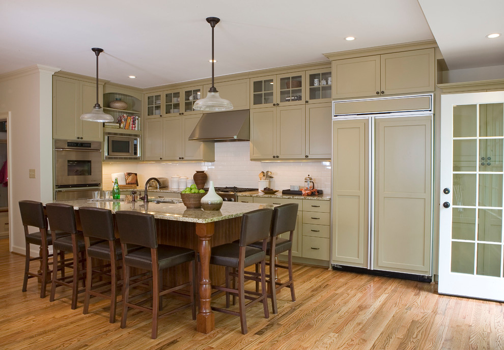 Ejemplo de cocinas en L clásica de obra con armarios estilo shaker, electrodomésticos con paneles, salpicadero de azulejos tipo metro y salpicadero blanco