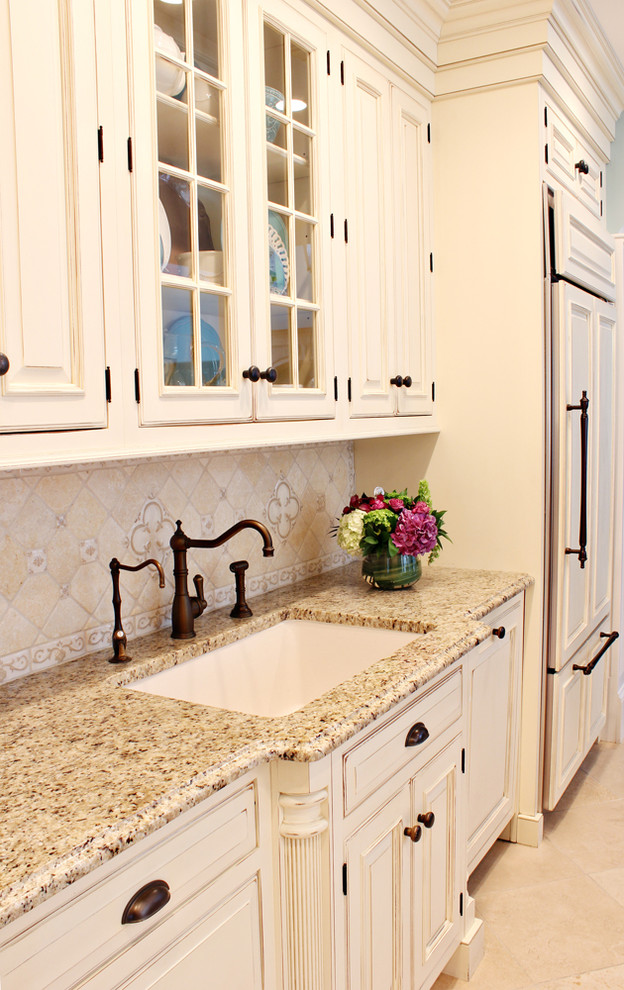 Example of a large classic l-shaped limestone floor eat-in kitchen design in Boston with a farmhouse sink, beaded inset cabinets, distressed cabinets, granite countertops, beige backsplash, mosaic tile backsplash, stainless steel appliances and an island