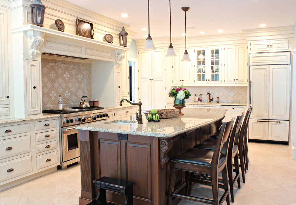 Eat-in kitchen - large traditional l-shaped limestone floor eat-in kitchen idea in Boston with a farmhouse sink, beaded inset cabinets, distressed cabinets, granite countertops, beige backsplash, mosaic tile backsplash, stainless steel appliances and an island