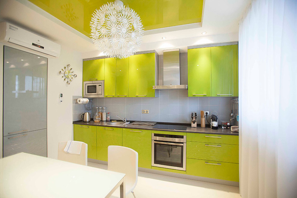 Contemporary l-shaped kitchen/diner in Moscow with a built-in sink, green cabinets, grey splashback and stainless steel appliances.