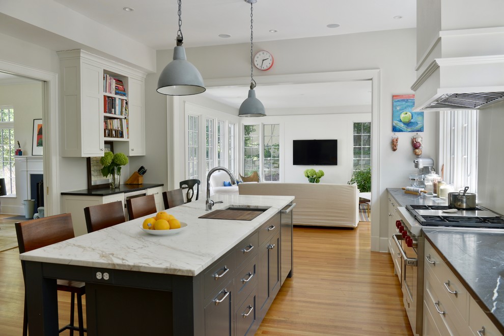 Foto på ett stort lantligt l-kök, med en undermonterad diskho, svarta skåp, rostfria vitvaror, mellanmörkt trägolv, en köksö, orange golv, skåp i shakerstil och marmorbänkskiva