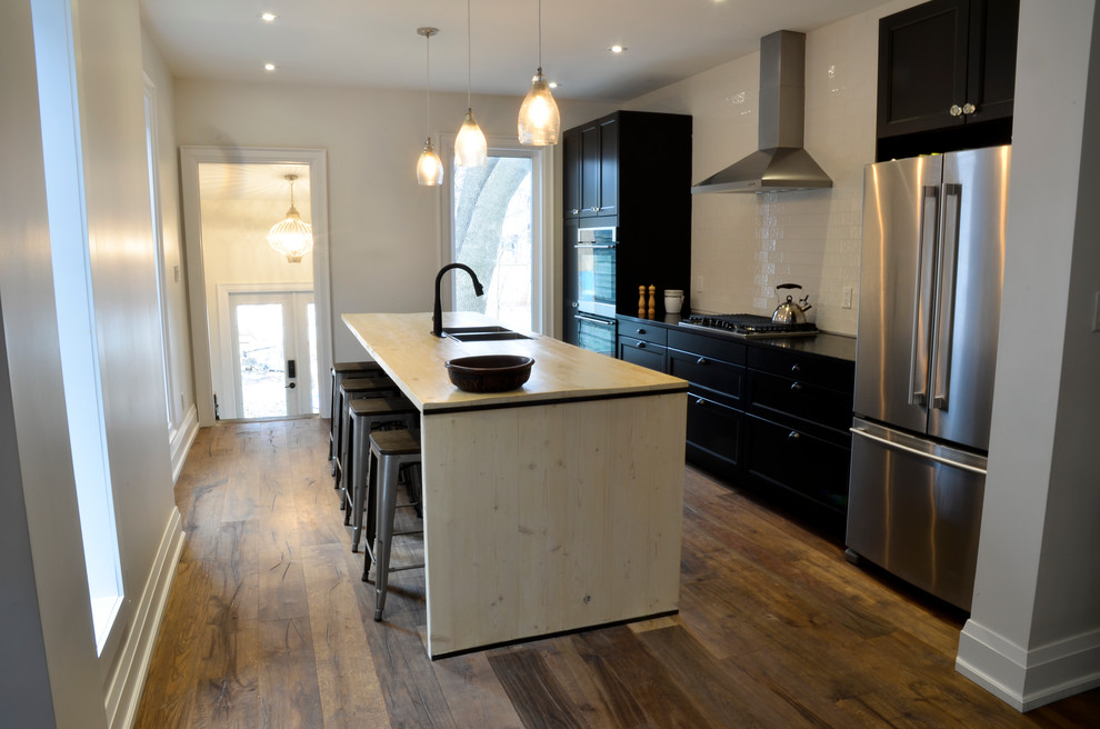 Design ideas for a medium sized eclectic single-wall kitchen/diner in Toronto with a submerged sink, recessed-panel cabinets, brown cabinets, white splashback, stainless steel appliances, medium hardwood flooring and an island.