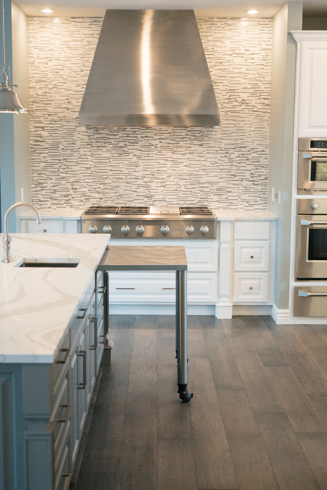 Example of a large transitional u-shaped dark wood floor and gray floor eat-in kitchen design in Other with a triple-bowl sink, raised-panel cabinets, white cabinets, quartz countertops, gray backsplash, marble backsplash, stainless steel appliances, two islands and white countertops
