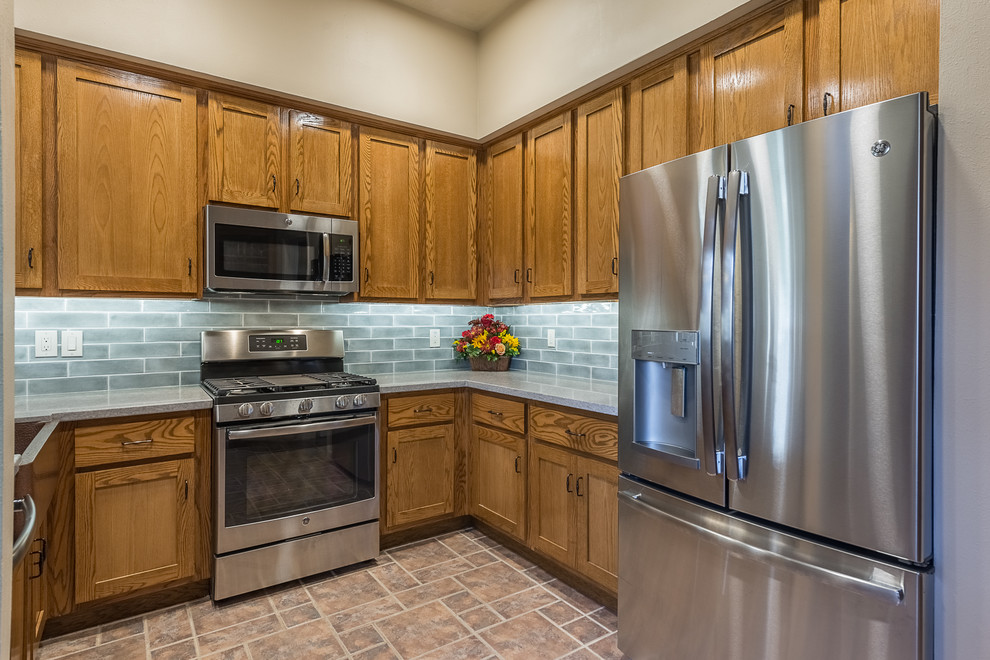 Enclosed kitchen - mid-sized traditional l-shaped ceramic tile and brown floor enclosed kitchen idea in Austin with a farmhouse sink, shaker cabinets, brown cabinets, granite countertops, gray backsplash, subway tile backsplash, stainless steel appliances, no island and gray countertops