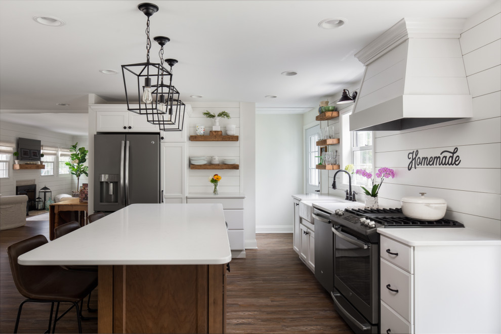 Foto på ett mellanstort lantligt vit kök, med en rustik diskho, skåp i shakerstil, vitt stänkskydd, stänkskydd i trä, en köksö, vita skåp, bänkskiva i kvarts, rostfria vitvaror, vinylgolv och brunt golv