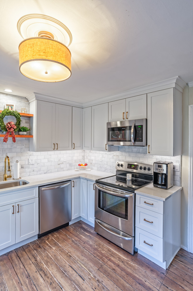 Bild på ett litet vintage vit vitt kök, med en undermonterad diskho, skåp i shakerstil, vita skåp, bänkskiva i kvarts, vitt stänkskydd, stänkskydd i marmor, rostfria vitvaror, mellanmörkt trägolv och brunt golv