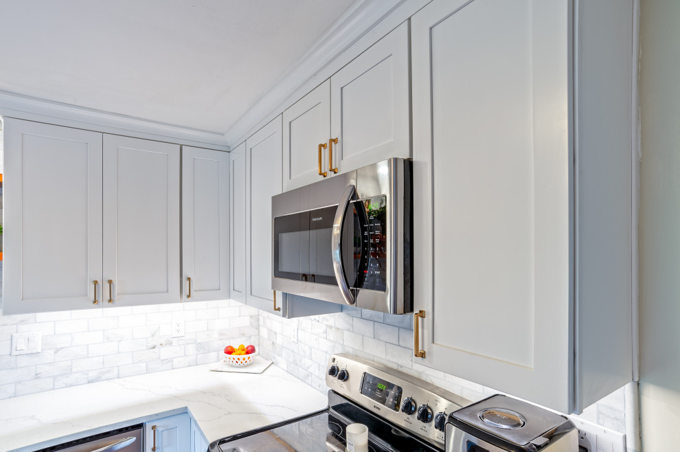 Inspiration for a small transitional l-shaped medium tone wood floor and brown floor eat-in kitchen remodel in Philadelphia with an undermount sink, shaker cabinets, white cabinets, quartz countertops, white backsplash, marble backsplash, stainless steel appliances, no island and white countertops
