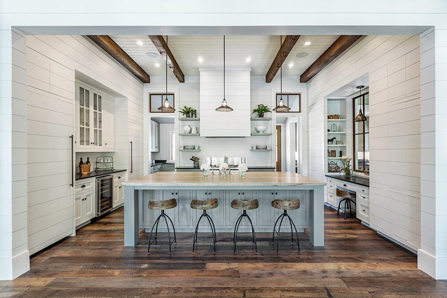 Large farmhouse galley kitchen/diner in Other with shaker cabinets, white cabinets, marble worktops, white splashback, wood splashback, integrated appliances, an island, a submerged sink and dark hardwood flooring.