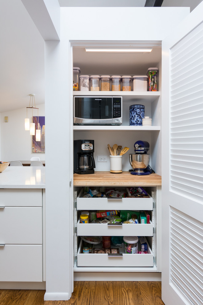 Large modern l-shaped kitchen pantry in Detroit with a submerged sink, flat-panel cabinets, white cabinets, blue splashback, metro tiled splashback, stainless steel appliances, medium hardwood flooring, an island, engineered stone countertops, brown floors and multicoloured worktops.