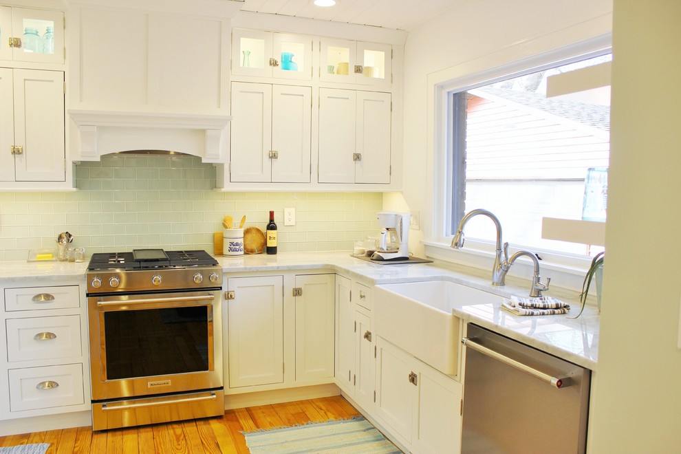 Example of a mid-sized farmhouse l-shaped light wood floor and brown floor eat-in kitchen design in Other with a farmhouse sink, beaded inset cabinets, white cabinets, marble countertops, green backsplash, glass tile backsplash, stainless steel appliances, no island and white countertops