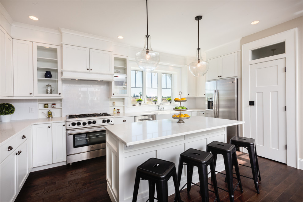 Open concept kitchen - mid-sized country u-shaped medium tone wood floor and brown floor open concept kitchen idea in Other with shaker cabinets, white cabinets, quartz countertops, white backsplash, porcelain backsplash, stainless steel appliances, an island and a farmhouse sink
