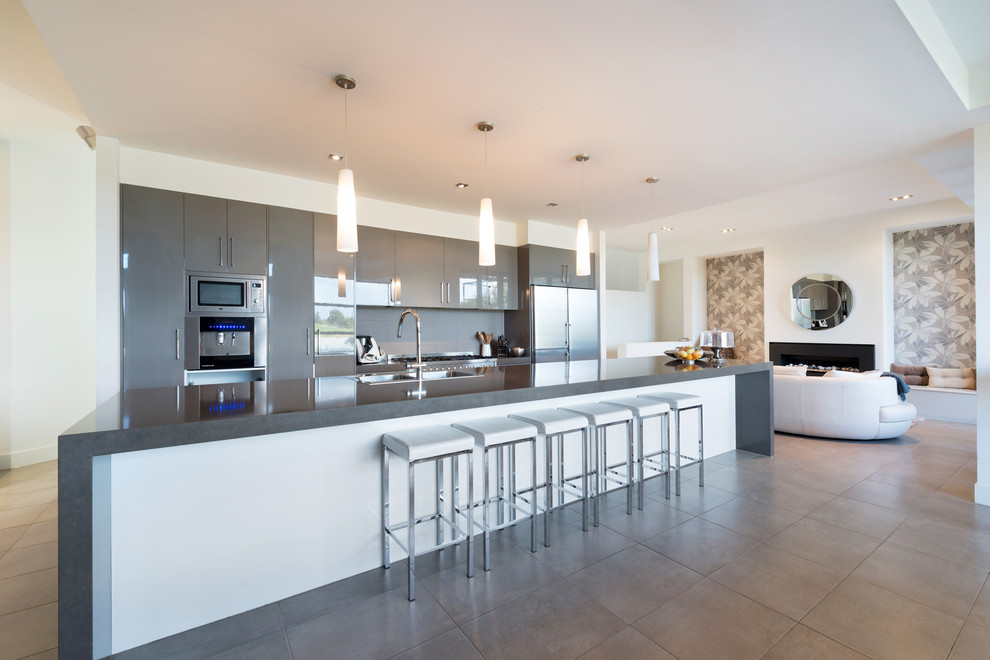 Источник вдохновения для домашнего уюта: большая прямая кухня-гостиная в современном стиле с двойной мойкой, серым фартуком, островом и бежевым полом