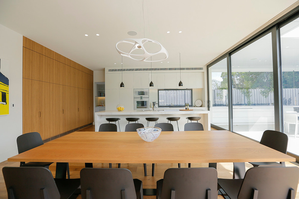 Idée de décoration pour une salle à manger ouverte sur la cuisine design de taille moyenne avec un sol en bois brun.