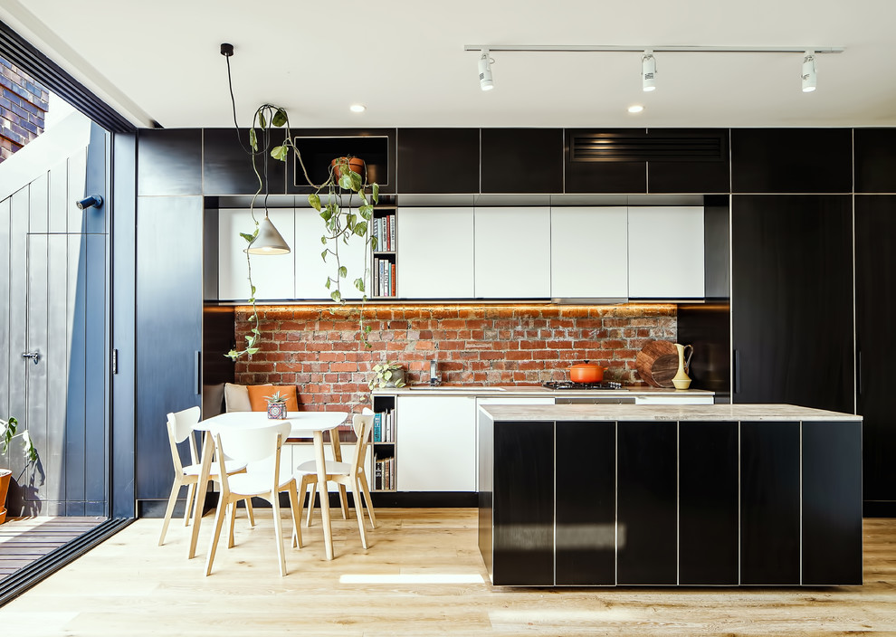Design ideas for a contemporary kitchen/diner in Melbourne with flat-panel cabinets, black cabinets, red splashback, brick splashback, light hardwood flooring, an island and beige floors.