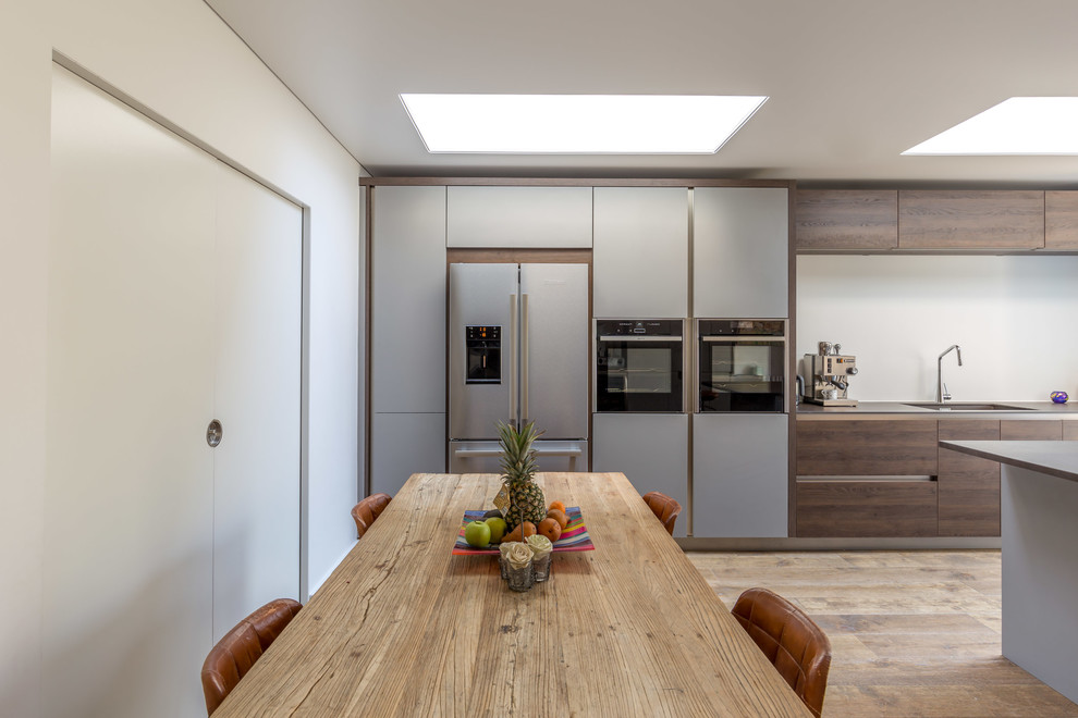 Inspiration for a medium sized contemporary single-wall kitchen in Sussex with flat-panel cabinets, brown cabinets, stainless steel appliances, bamboo flooring and an island.