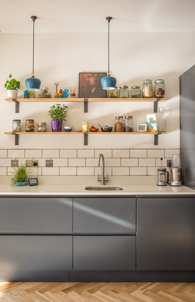 Inspiration for a contemporary light wood floor and brown floor kitchen remodel in Sussex with an undermount sink, flat-panel cabinets, gray cabinets, white backsplash and subway tile backsplash