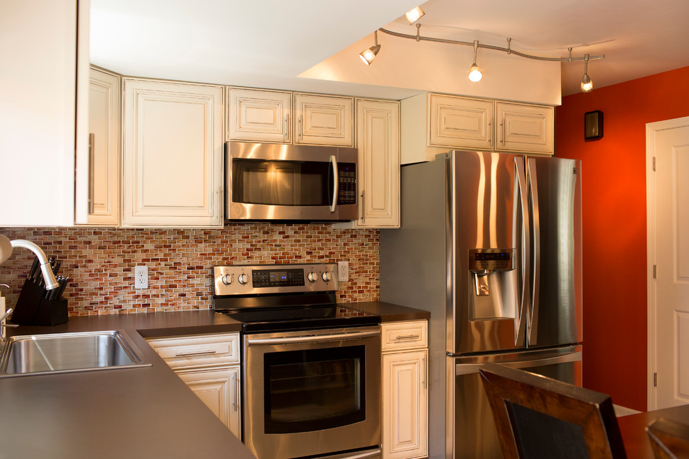 Foto di una cucina minimal di medie dimensioni con lavello da incasso, ante con riquadro incassato, ante bianche, top in laminato, paraspruzzi marrone e elettrodomestici in acciaio inossidabile