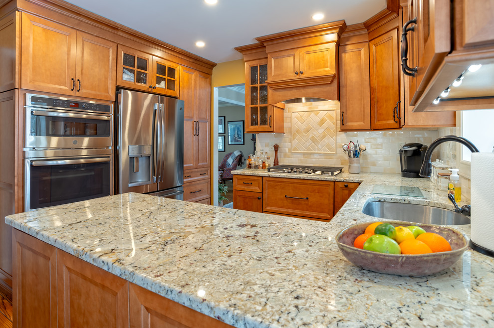 Example of a mid-sized classic u-shaped medium tone wood floor and brown floor eat-in kitchen design in Philadelphia with an undermount sink, recessed-panel cabinets, light wood cabinets, quartzite countertops, multicolored backsplash, window backsplash, stainless steel appliances, a peninsula and beige countertops