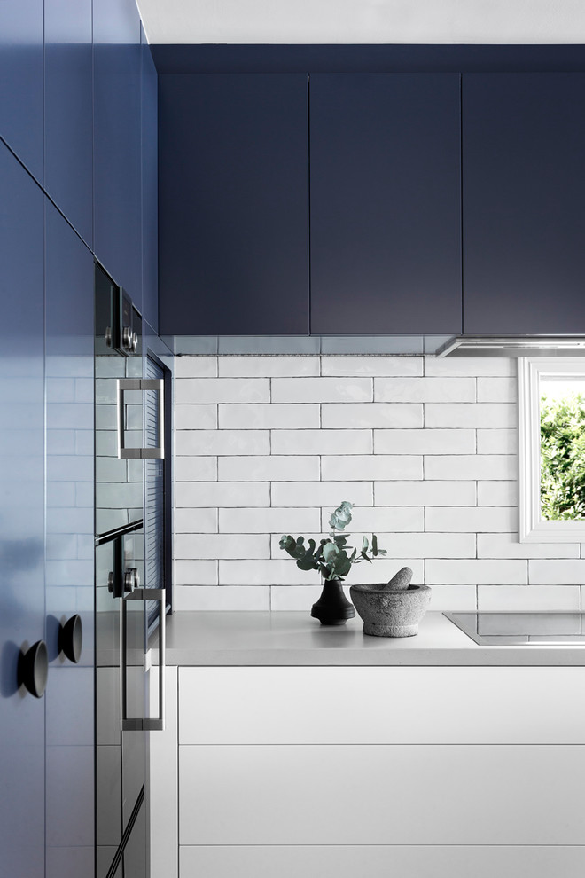 Exempel på ett mellanstort modernt kök, med en undermonterad diskho, släta luckor, blå skåp, bänkskiva i kvarts, vitt stänkskydd, fönster som stänkskydd, svarta vitvaror och mörkt trägolv