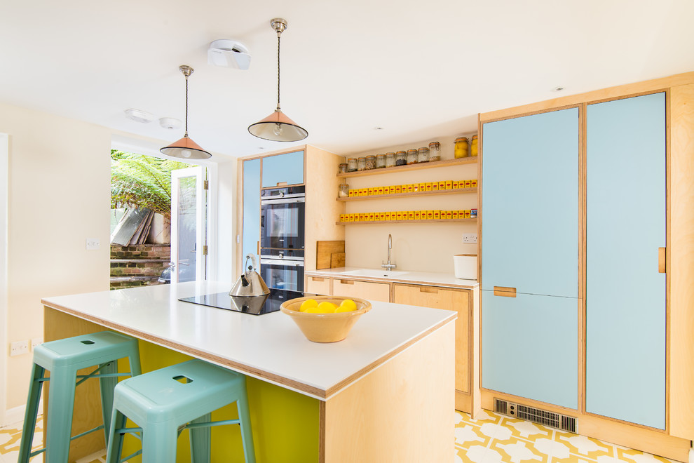 Zweizeilige Moderne Küche mit Unterbauwaschbecken, flächenbündigen Schrankfronten, blauen Schränken, Küchenrückwand in Weiß, Elektrogeräten mit Frontblende, Kücheninsel, buntem Boden und weißer Arbeitsplatte in Sussex