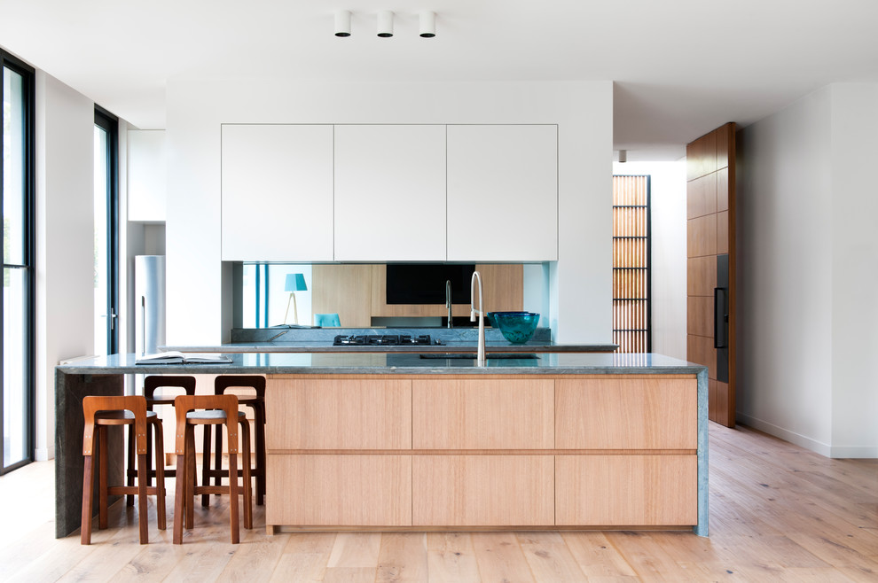 Zweizeilige Moderne Küche mit flächenbündigen Schrankfronten, hellbraunen Holzschränken, Rückwand aus Spiegelfliesen, braunem Holzboden, Kücheninsel und braunem Boden in Melbourne
