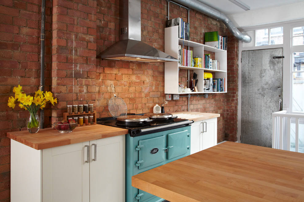 Medium sized urban u-shaped kitchen/diner in London with a belfast sink, shaker cabinets, white cabinets, wood worktops, stainless steel appliances, medium hardwood flooring and a breakfast bar.
