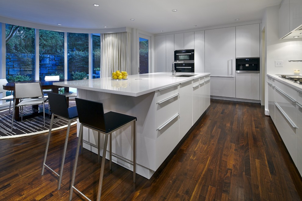 Example of a trendy l-shaped dark wood floor eat-in kitchen design in Atlanta with an undermount sink, flat-panel cabinets, white cabinets, quartz countertops, glass sheet backsplash, stainless steel appliances and an island