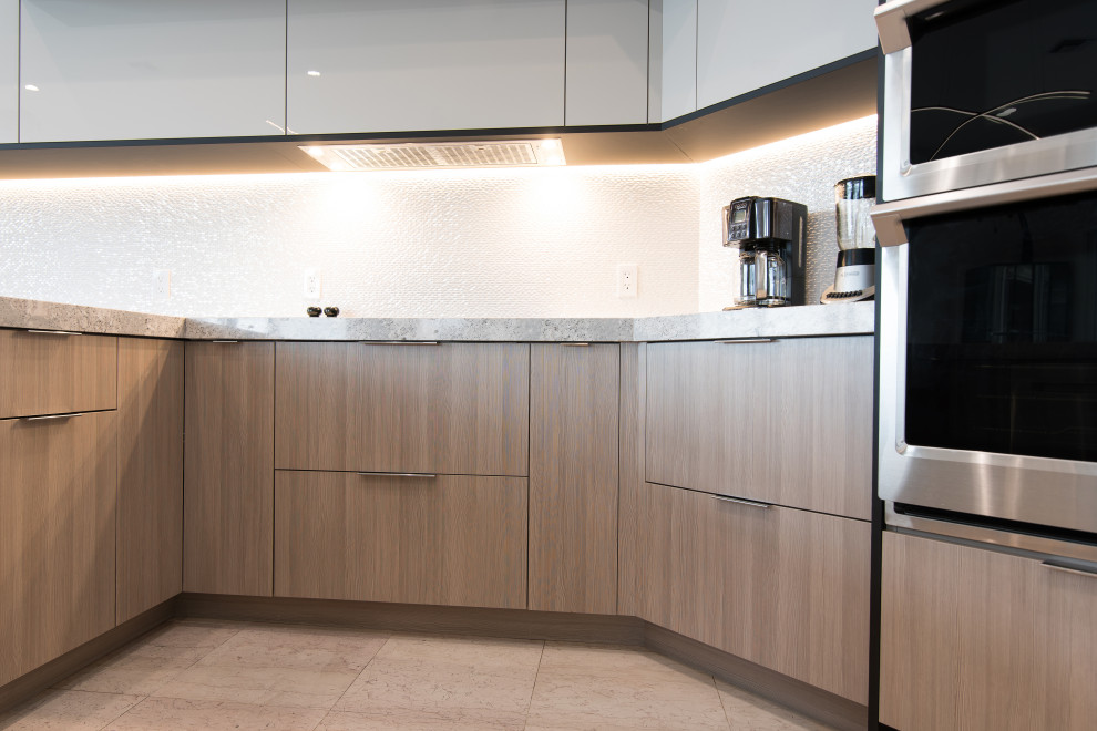 Large contemporary l-shaped open plan kitchen in Miami with a submerged sink, flat-panel cabinets, grey cabinets, engineered stone countertops, white splashback, porcelain splashback, stainless steel appliances, an island and grey worktops.