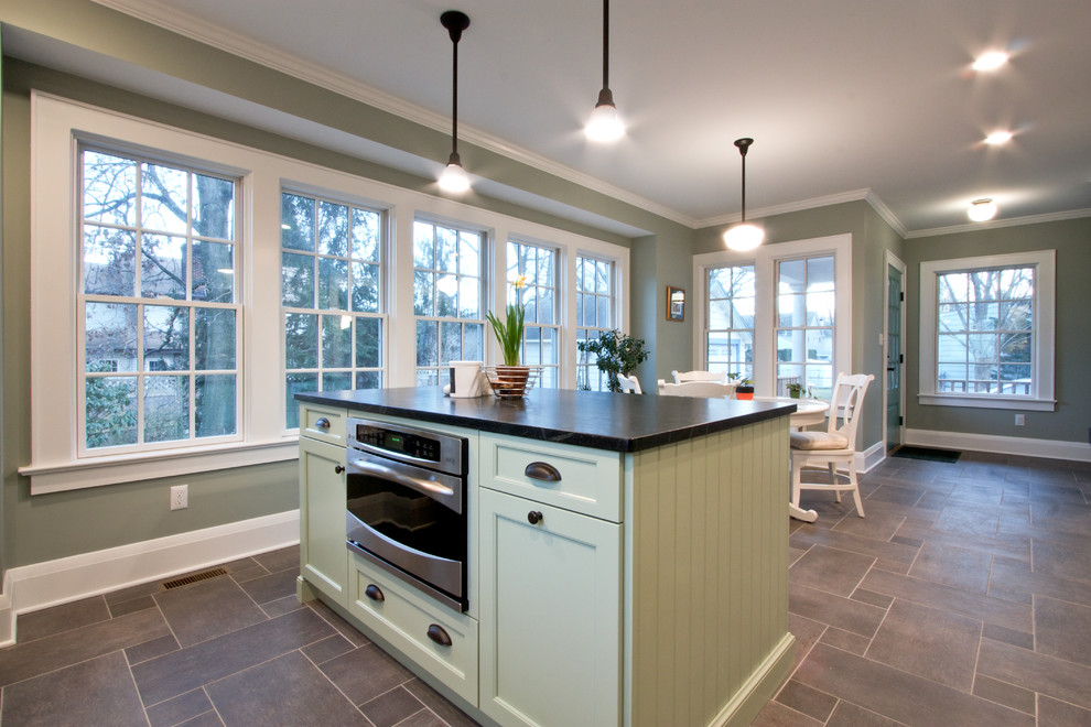 Eat-in kitchen - contemporary galley eat-in kitchen idea in Newark with a farmhouse sink, shaker cabinets, white cabinets, soapstone countertops, white backsplash, subway tile backsplash, stainless steel appliances and an island