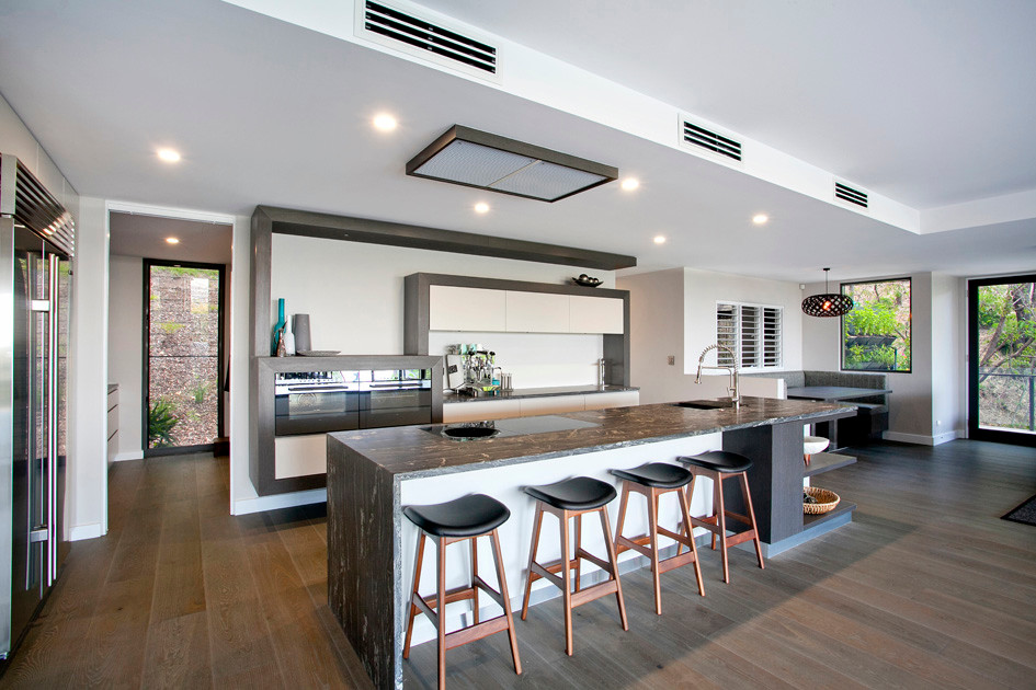 Inspiration for a large contemporary single-wall kitchen/diner in Brisbane with a submerged sink, flat-panel cabinets, white cabinets, laminate countertops, white splashback, stainless steel appliances, medium hardwood flooring and an island.