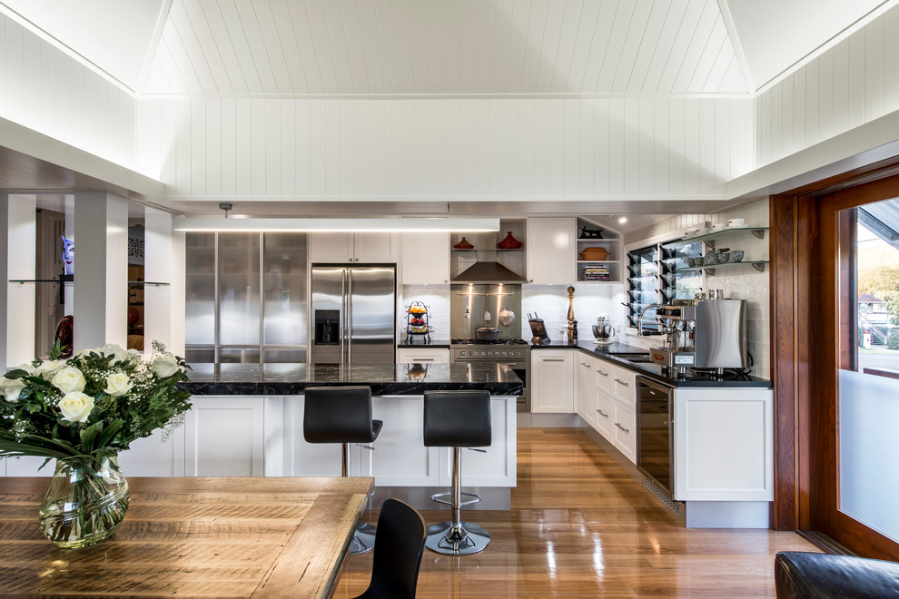 Bild på ett funkis kök, med luckor med infälld panel, vita skåp, vitt stänkskydd, stänkskydd i tunnelbanekakel och rostfria vitvaror