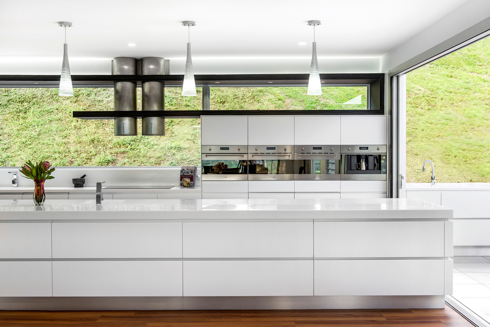 Moderne Küche mit flächenbündigen Schrankfronten, weißen Schränken und Küchengeräten aus Edelstahl in Brisbane