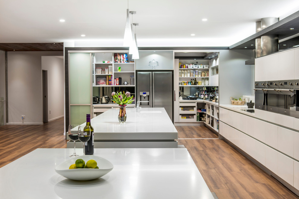 Cette image montre une cuisine design en L avec un placard sans porte, des portes de placard blanches et un électroménager en acier inoxydable.